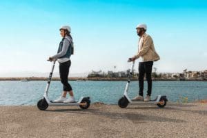 Two people riding Bird Scooters on the waterfront