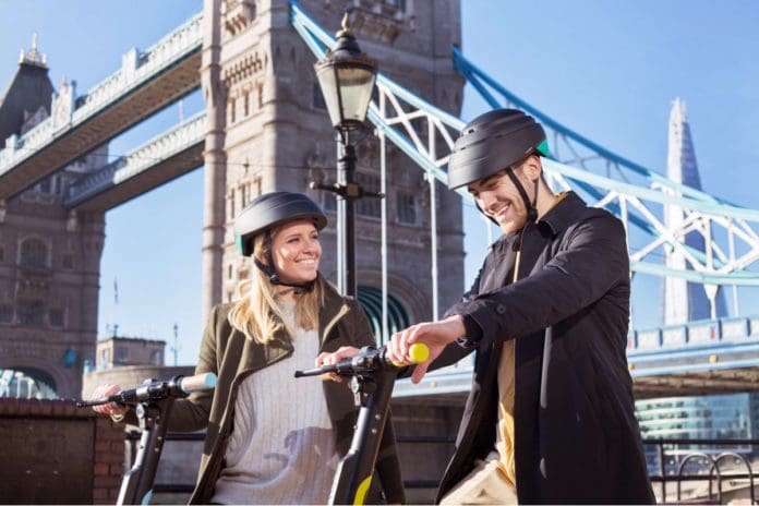 Man and woman riding Dott eScooters in London