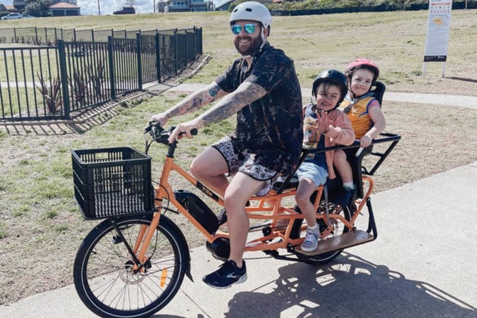 Family riding two-wheeled cargo bike