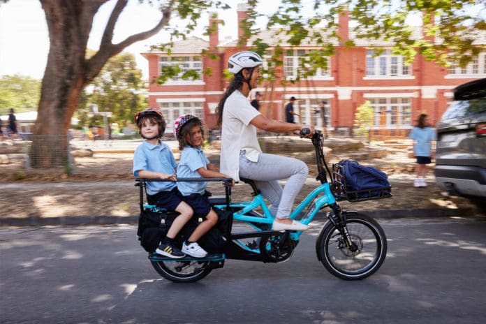 woman and two kids riding cargo bike