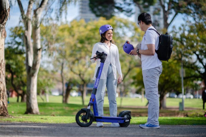 Two people standing with e-scooter