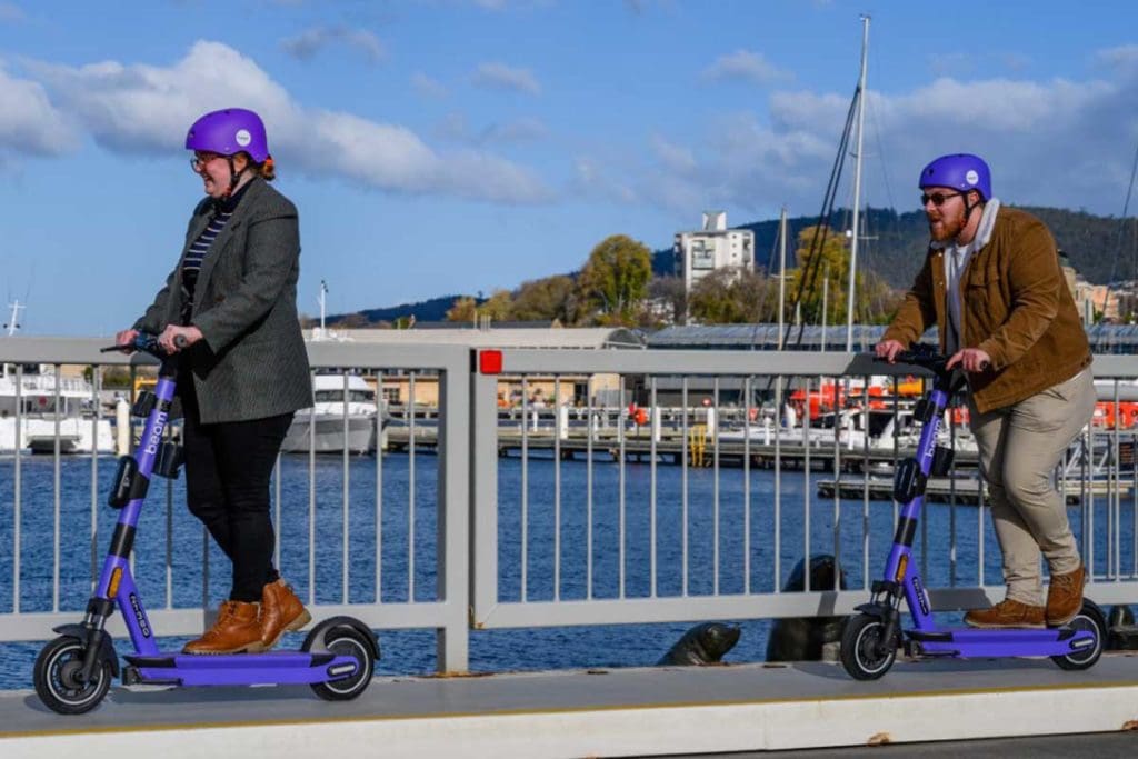 two people riding e-scooters in the city
