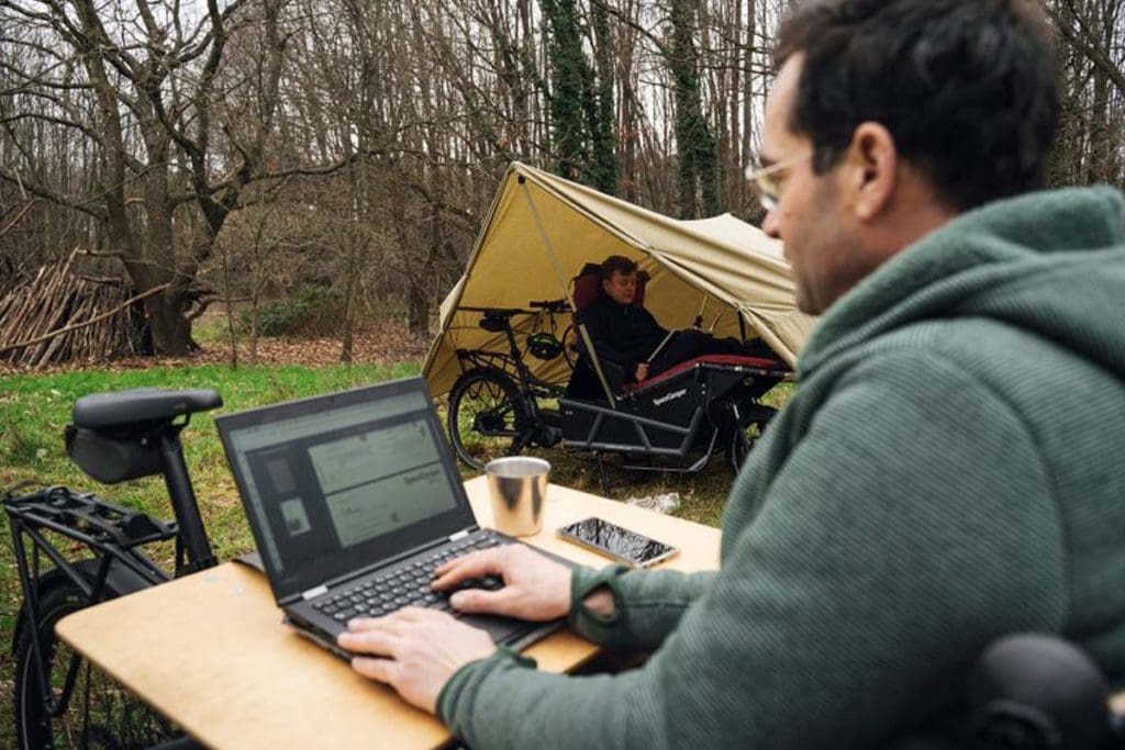 Man working on laptop at campsite