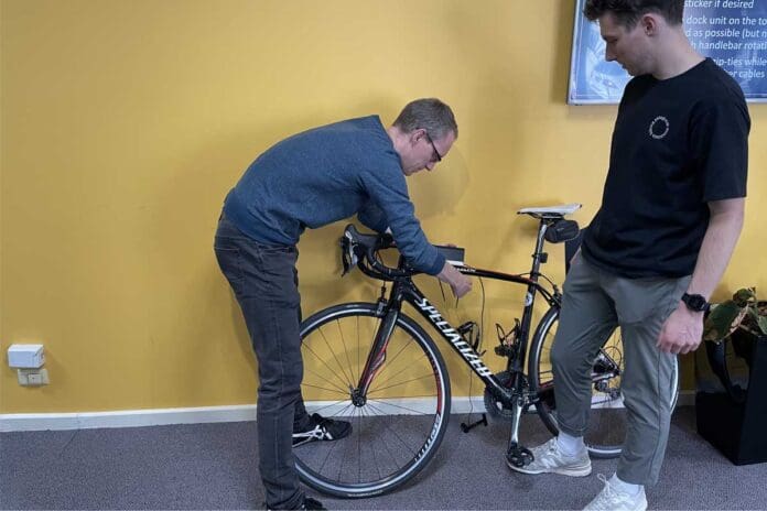 Two people mounting velograph to bike