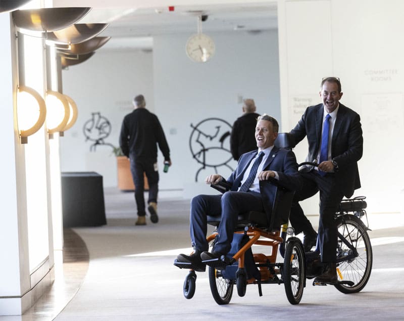 Two parliamentarians riding mobility devices