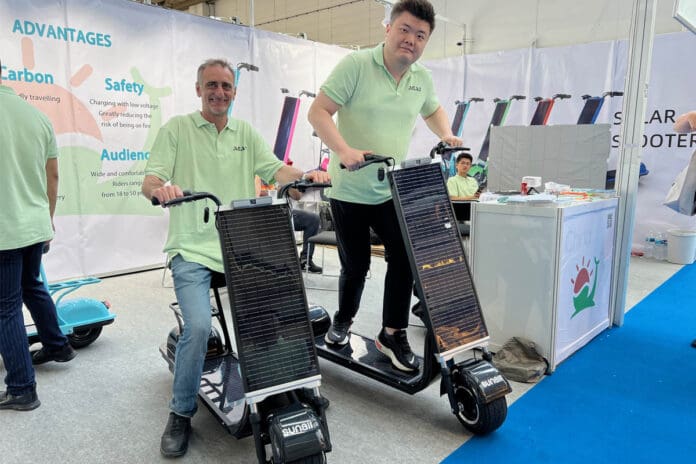 Two men demonstrating solar scooters at expo