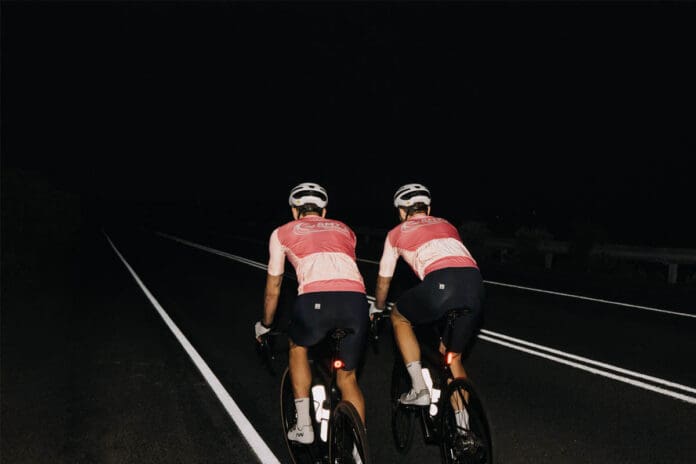 Two people riding road bikes at night