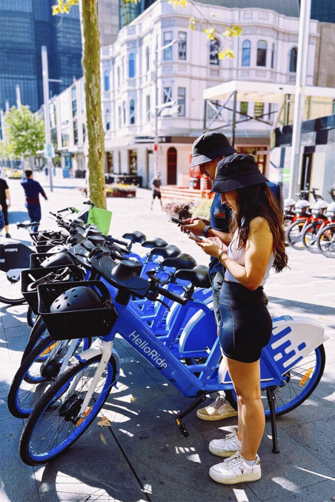 Two people using app for shared e-bike service on city street