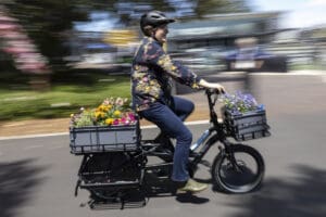 Woman riding e-bike with flowers in the front and back carry section