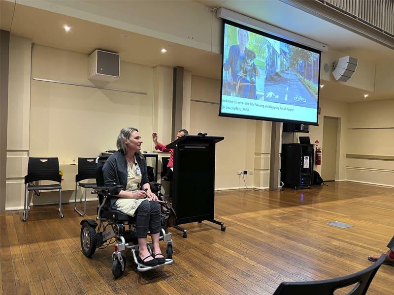 Woman sitting in mobility device presenting at conference