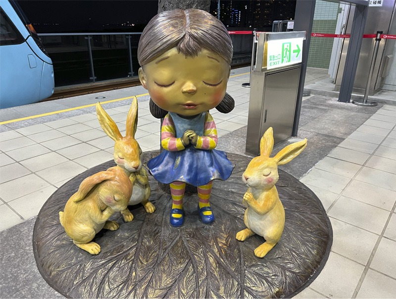 large children's character sculpture of a girl standing with three rabbits