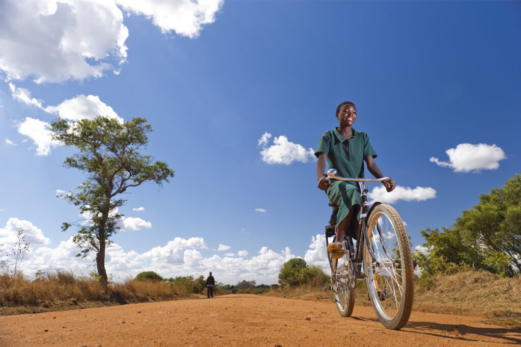 School girl riding a bike on dirt path in rural Africa