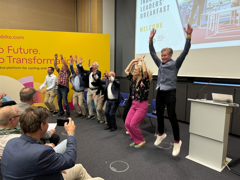 Group of people at the front of a conference room jumping into the air.