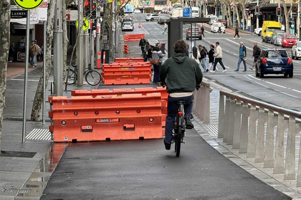 Person bike riding on protected bike lane under construction.