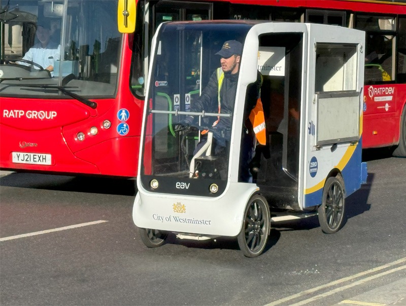 A four wheeled electric cargo bike riding on street