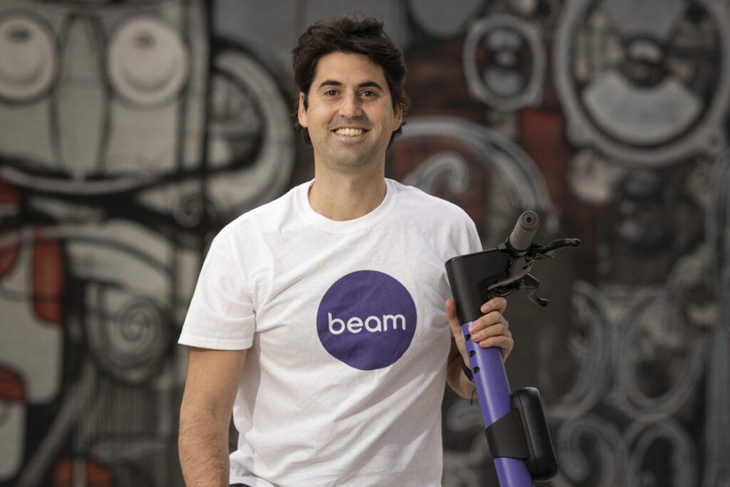 Portrait of Tom Cooper with an e-scooter wearing Beam shirt