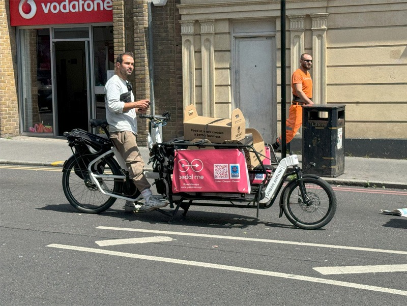 Person riding a cargo bike loaded with parcels