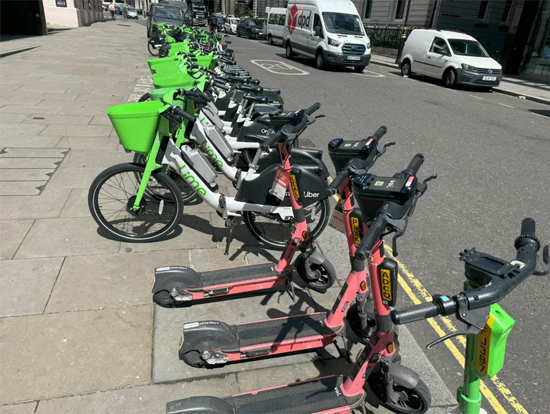 Share E-scooters and bikes lined up on street