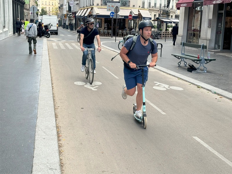 Scooter rider and cyclist riding on a cycling path.