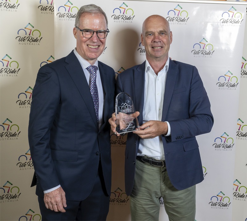 Two people standing for portrait with a trophy.